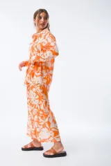 Pantalón palazzo naranja con estampado de hojas blancas, cintura elástica y corte amplio.