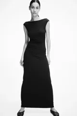 Vestido largo negro de punto elástico con leve brillo, corte entallado, escote drapeado, espalda escotada y pliegues laterales.