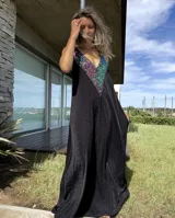 Vestido largo negro con escote en V y breteles finos. Presenta un aplique de lentejuelas multicolores en el escote.