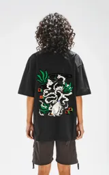 Remera negra de corte oversize con hombros caídos y cuello redondo. Estampado en la espalda con diseño de gatos fumando, hojas de marihuana y manos rezando.