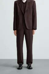 Pantalón de vestir color marrón oscuro, de corte recto, con bolsillos laterales y traseros de doble vivo. Se ajusta a la cintura con cierre de cremallera y botón.