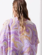 Kimono tejido con estampado abstracto en tonos verde, azul y blanco. Tiene mangas cortas amplias y terminación con borlas verdes en el ruedo.