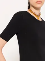Top negro tejido en hilado frío con calce al cuerpo, mangas cortas y abertura en la espalda que se ata en el cuello.