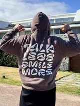 Canguro marrón con capucha y estampado blanco en la espalda con la frase "Talk Less Smile More".