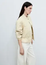 Chaqueta acolchada color verde militar con cuello perkins, cierre frontal con botones, dos bolsillos laterales y detalle fruncido en el bajo. Estilo bomber.