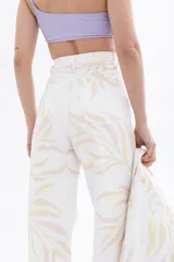Pantalón jean blanco con estampado de hojas en tonos pastel.