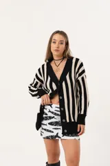 Saco oversize tejido a rayas verticales en blanco y negro, con escote en V y botones.