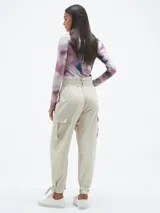 Pantalón color beige claro, de corte holgado, con bolsillos laterales y cinturón con hebilla metálica.
