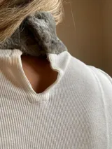 Polera color beige de lycra con cuello alto y puños de piel sintética color borgoña.