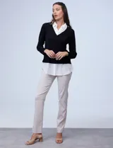 Buzo de hilado fino color beige con cuello y ruedo de gasa blanca que simula una camisa debajo. Presenta escote en V y mangas largas.