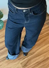 Pantalón de jean azul oscuro de corte ancho con dobladillo en color gris claro.
