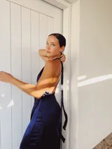 Vestido largo azul con escote halter cruzado, abertura en el pecho, falda drapeada con flecos y corte irregular.