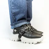 Zapatillas negras aterciopeladas con suela alta y accesorio extraíble con hebillas.