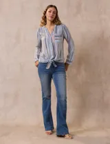 Blusa de gasa estampada a rayas verticales en tonos celeste, lila, naranja y marrón. Tiene cuello a la base con escote en V y botones. Delantera con bolsillo aplicado. Largo de manga regulable con presilla y botón. Terminación anudada opcional.