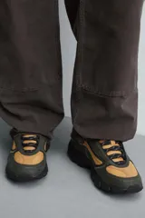 Zapatillas deportivas color crema con cordones, suela gruesa con diseño irregular y detalles en gris.