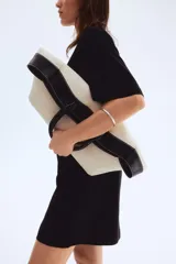 Vestido corto negro de punto de algodón suave con cuello redondo ribeteado acanalado, hombros caídos y mangas al codo. Pinzas moldeadoras en la parte posterior de la cintura para estilizar la figura.