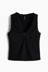 Top corto negro en punto suave con efecto arrugado, escote de pico con moño de satén y costura fruncida.