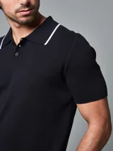 Remera tejida tipo polo color negro, de corte regular fit, con cuello y puños con ribete en contraste de color blanco, cartera con tres botones y logo bordado en la pechera.