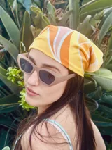 Pañuelo de tela satinada color amarillo con estampado de líneas curvas en tonos naranja, blanco y rosa.