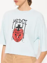 Remera gris con estampa de una mariquita y la palabra "Merci" en el frente.