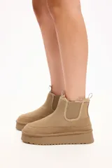 Bota tipo chelsea de gamuza color camel, con interior forrado en piel sintética y paneles elásticos laterales. Cuenta con una plataforma alta y suela dentada.