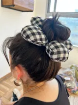 Colita de pelo acolchonada con forma de flor, con estampado vichy blanco y negro.