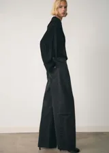 Pantalón de jean negro de corte wide leg, tiro bajo y bajo deshilachado. Cuenta con cierre de cremallera y botón, trabillas, cinco bolsillos y costuras decorativas.