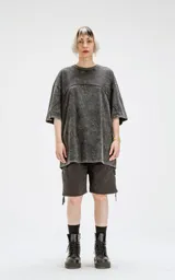 Remera de cuello redondo, calce oversize, color gris oscuro con efecto batik artesanal (acid wash). Presenta un corte curvo en la parte superior del pecho que simula un recorte.