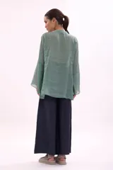 Camisa verde agua con cuello mao, abotonada al frente y mangas largas acampanadas con puños elásticos.
