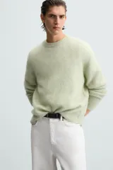 Sweater verde claro tejido con lana y alpaca, de corte regular, cuello redondo y manga larga con terminaciones en rib.