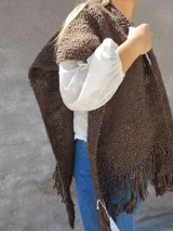 Ruana marrón tejida a mano con lana merino, con flecos en el borde inferior.