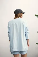 Blazer celeste de lino con solapas de muesca, cierre cruzado con botones, bolsillos delanteros con solapa y corte holgado.