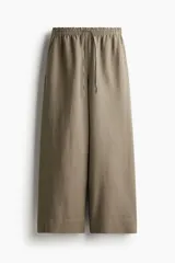 Pantalón de corte holgado color arena, confeccionado en tejido liviano de mezcla de lino. Modelo de tiro alto con elástico revestido en la cintura, cordón para ajustar fino y piernas amplias con bolsillos al bies.