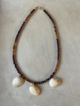 Collar largo de cuentas de piedras semipreciosas en tonos tierra, con dijes de conchas marinas.