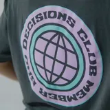 Remera blanca de algodón con estampa circular en la espalda con un globo terráqueo en color lila y texto "Bad Decisions Club Member" en negro y celeste.