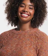 Suéter de punto melange color naranja con hilos metalizados, cuello redondo y mangas largas raglán.