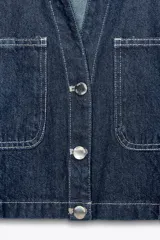 Camisa corta de denim azul con cuello solapa, escote pico, manga corta, bolsillos delanteros de plastrón y cierre frontal con botones metálicos.