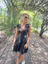 Vestido corto negro con breteles finos, escote en V, espalda descubierta con lazo y falda con volados.