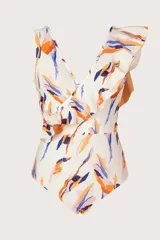 Traje de baño entero blanco con estampado abstracto en tonos naranja, azul y rosado. Presenta escote en V cruzado y un volado asimétrico que cae sobre un hombro.