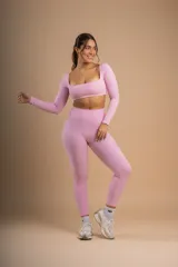 Conjunto deportivo color beige compuesto por calza de tiro alto y top de manga larga con escote cuadrado y logo bordado en el pecho.