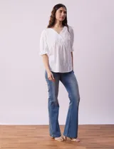 Blusa blanca calada con escote en V, mangas cortas con hombros fruncidos y puños elastizados.