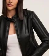 Campera negra de cuero sintético con cuello mao, cierre frontal con cremallera y mangas largas con detalle de pespuntes horizontales.
