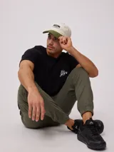 Gorra de lona lavada color beige con visera verde y parche con el logo de Rusty en el frente.