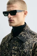 Cazadora corta (cropped fit) de piel con acabado de pelo, estampado abstracto en tonos negro y beige/tostado. Presenta cuello solapa, manga larga y cierre frontal con botones metálicos.