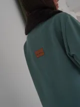 Campera corta negra con cuello y puños de piel sintética negra. Cierre con presillas de madera.