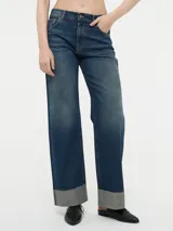 Pantalón de jean azul oscuro, de corte ancho y tiro alto, con bolsillos delanteros y traseros, y dobladillo en el ruedo.