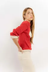 Sweater rojo tejido a mano con hilo, de corte holgado y cuello redondo. Presenta detalles en color crudo en el cuello, puños y ruedo.