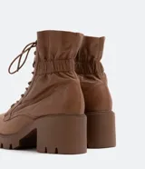 Bota de cuero color marrón con cordones, caña media con detalle de elástico en la parte trasera, taco bloque medio y suela track.