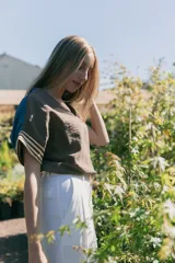 Blusa marrón con cuello en V, mangas cortas con detalle de tela rayada en los puños y corte holgado.