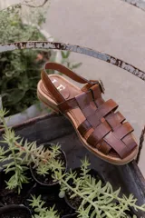 Sandalias de cuero marrón con tiras entrecruzadas y hebilla dorada al tobillo.